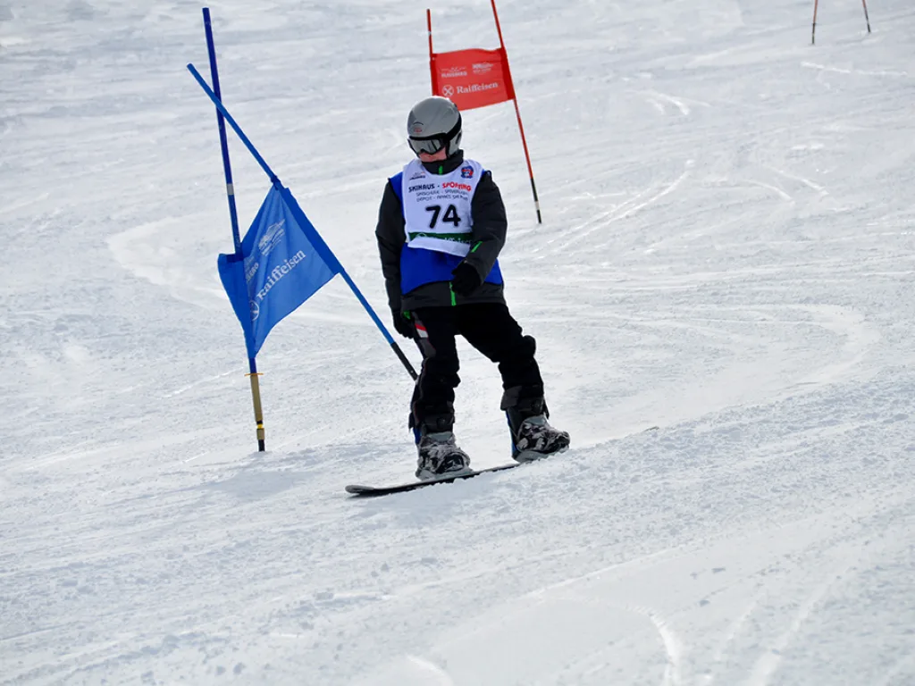 Snowboarder mit Startnummer 74 am blauen Tor.